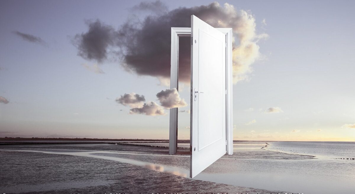 Eine geöffnete Tür steht an einem einsamen Strand. Über dem Meer türmen sich Wolken.